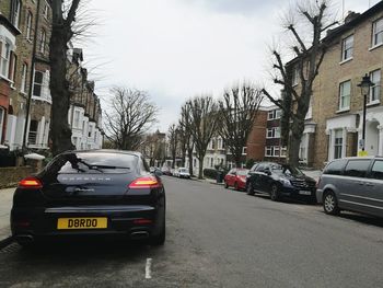 Cars on city street against sky