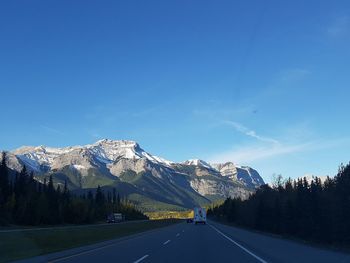 Road by mountains against clear blue sky