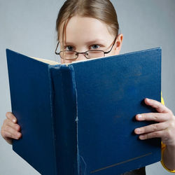 Portrait of girl with book sitting against gray background