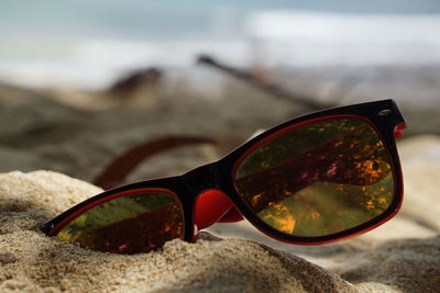 Close-up of sunglasses on glass at beach