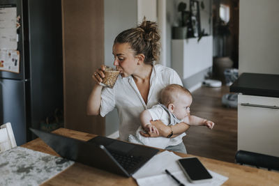 Multitasking mother taking care of baby and working from home