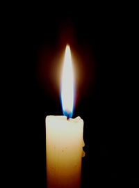 Close-up of lit candle in dark room