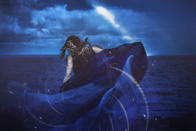 Side view of woman on sea shore against sky