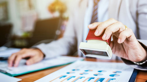 Midsection of man using smart phone on table