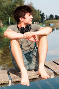 Portrait of young man sitting by lake