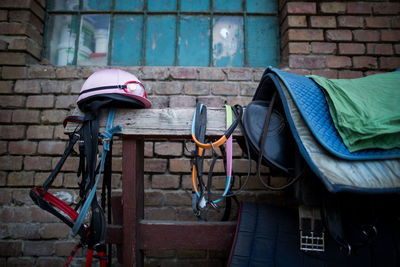 Saddles and bridles with helmet on wood against stable
