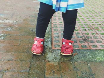 Low section of girl standing on street during rainy season