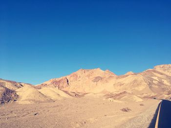 Scenic view of desert against clear blue sky