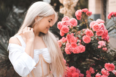 Side view of young woman standing amidst flowers