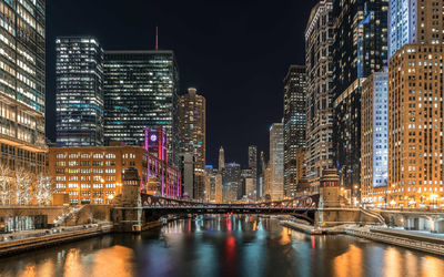 Chicago river amidst illuminated buildings in city at night
