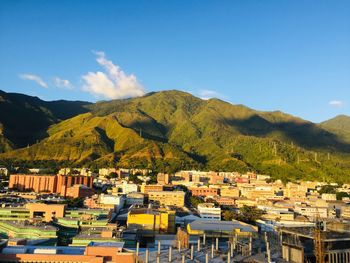 Townscape by mountains against blue sky