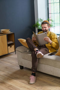 Young woman using laptop while sitting on sofa at home