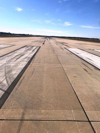 Tire tracks on airport runway against sky