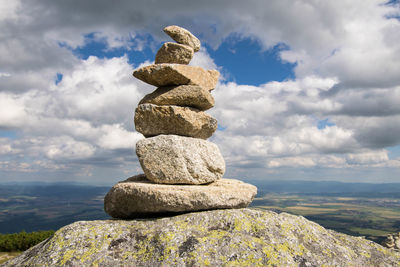 Stack of stones on rock against sky