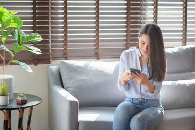 Full length of young woman using mobile phone