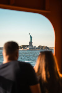 Rear view of woman standing by sea against sky during sunset