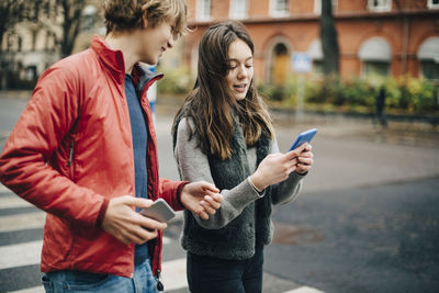 Full length of woman using mobile phone in city