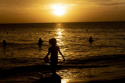 Silhouette people on beach against sky during sunset