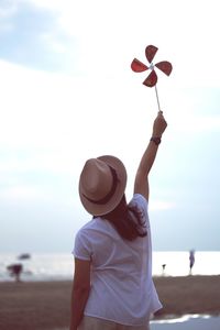 Rear view of woman holding pinwheel toy at beach