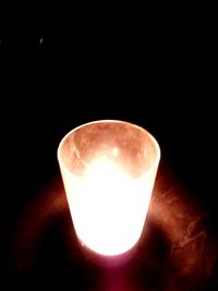 Close-up of illuminated light bulb against black background