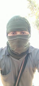 Portrait of young man covering face against sky