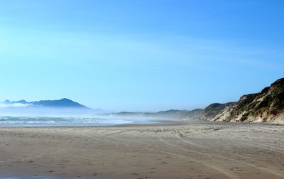 Scenic view of beach against clear blue sky