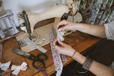 Cropped hand of woman using sewing machine