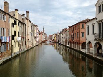 Canal amidst buildings against sky