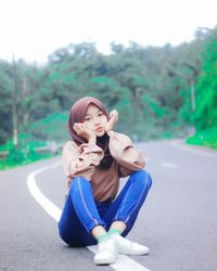 Portrait of young woman sitting on road