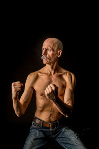 Senior fighter practicing against black background