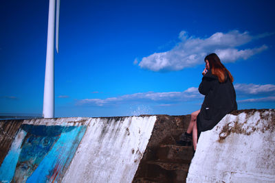 Woman standing against blue sky