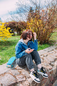 Side view of woman sitting on footpath