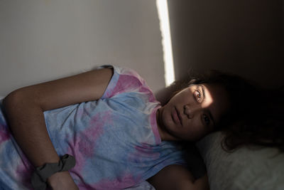 Young ethnic woman with a line of light illuminating her eyes lying on bed