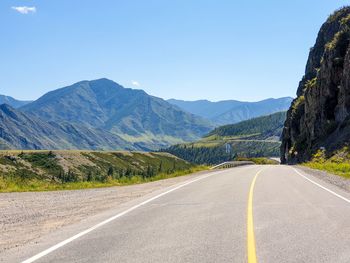 Road leading towards mountains against clear sky