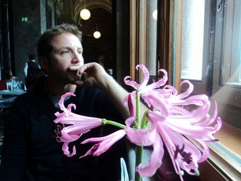 Close-up of young man sitting in pink indoors