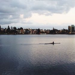 Boat sailing in river against cloudy sky