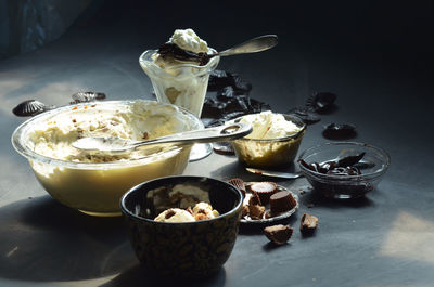 High angle view of ice cream in bowls with peanut butter cupcakes and chocolates on table