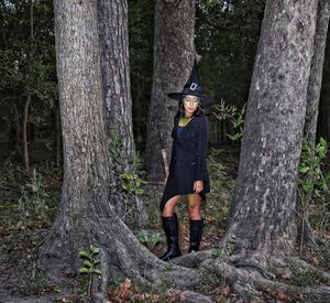 Woman standing by tree trunk in forest