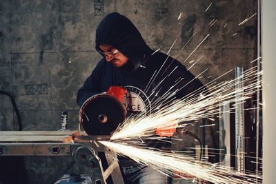 Manual worker cutting metal while working in workshop