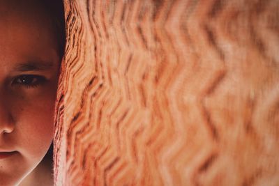 Close-up portrait of girl by curtain