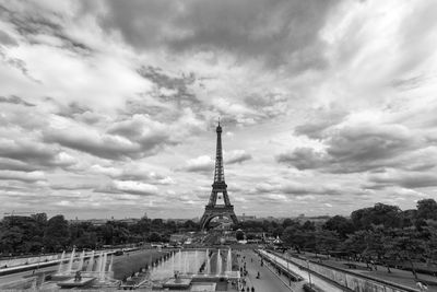 Communications tower in city against cloudy sky