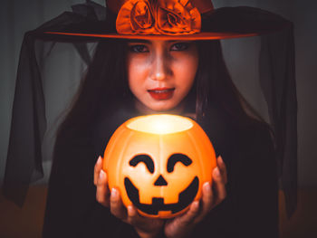 Portrait of a smiling woman with pumpkin at home