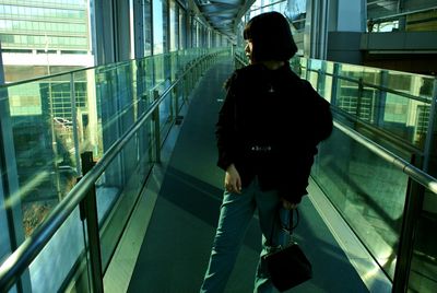 Woman wearing jacket looking away while standing on footbridge