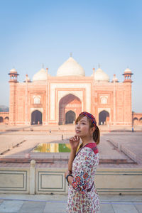 Woman looking away while standing against taj mahal