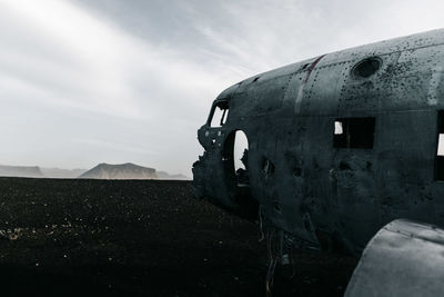 Abandoned airplane on field against sky