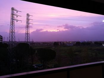 Silhouette trees and electricity pylon against sky