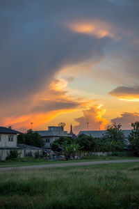 Factory on field against sky during sunset