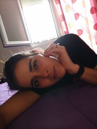 Portrait of young woman lying on bed at home