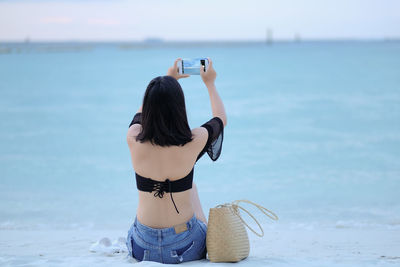 Rear view of woman photographing sea