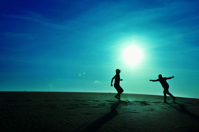 Silhouette people on beach against sky